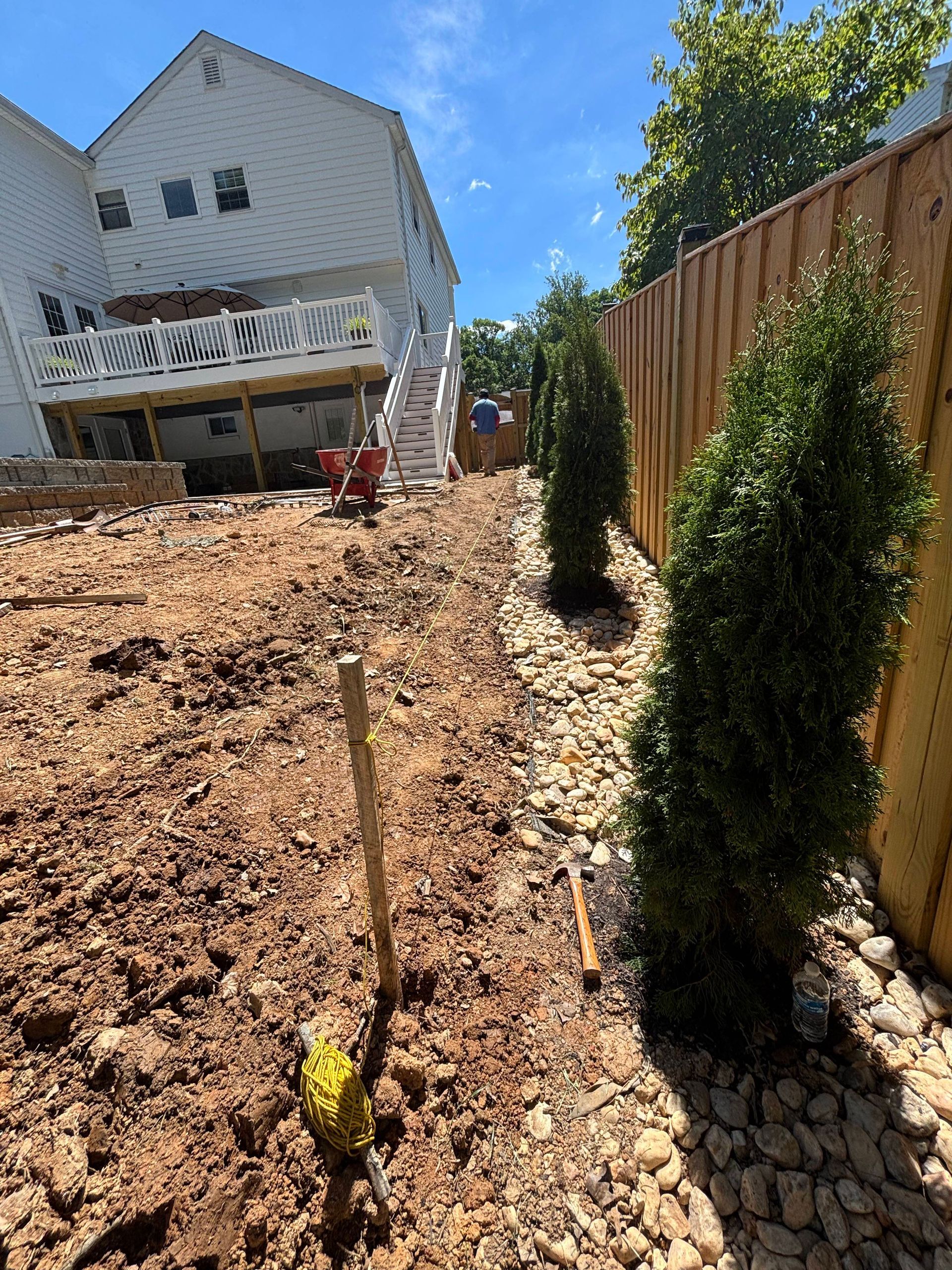 Backyard slope with fresh mulch, young shrubs, and a house with a raised deck in the background
