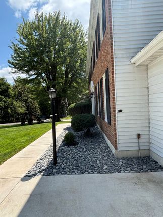 Concrete patio beside a house with steps to a sliding glass door and a patch of dirt in front