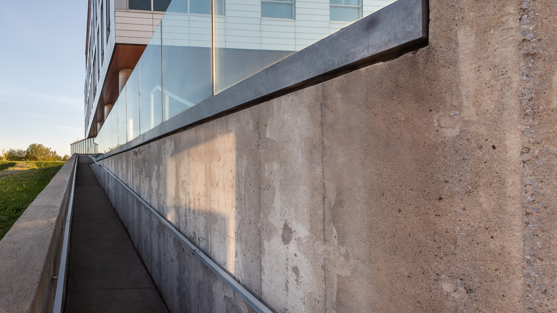 A ramp leading to the side of a building with a glass railing.