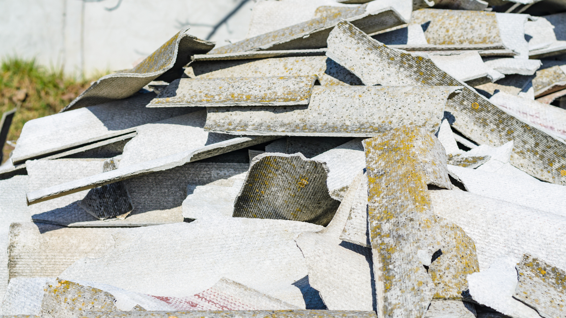 A pile of pieces of asbestos sitting on top of a sidewalk.