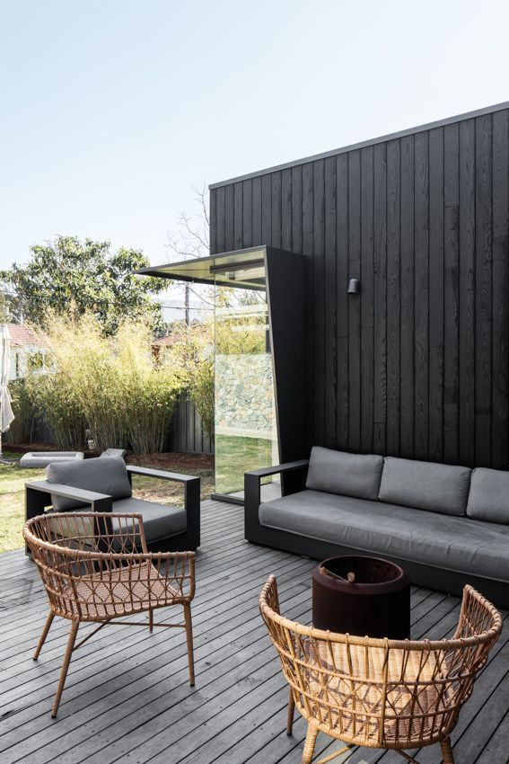 Outdoor patio with gray wooden deck, black wall, and modern seating — Make The Mark Building Services in Illawarra, NSW