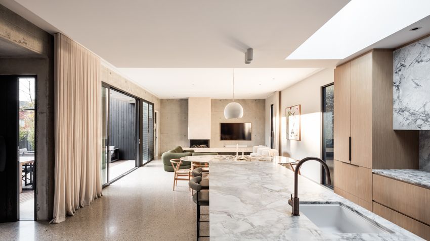 Modern open-plan kitchen and living area with light wood cabinets, marble counters, and sliding glass doors to a dark patio — Make The Mark Building Services in Illawarra, NSW