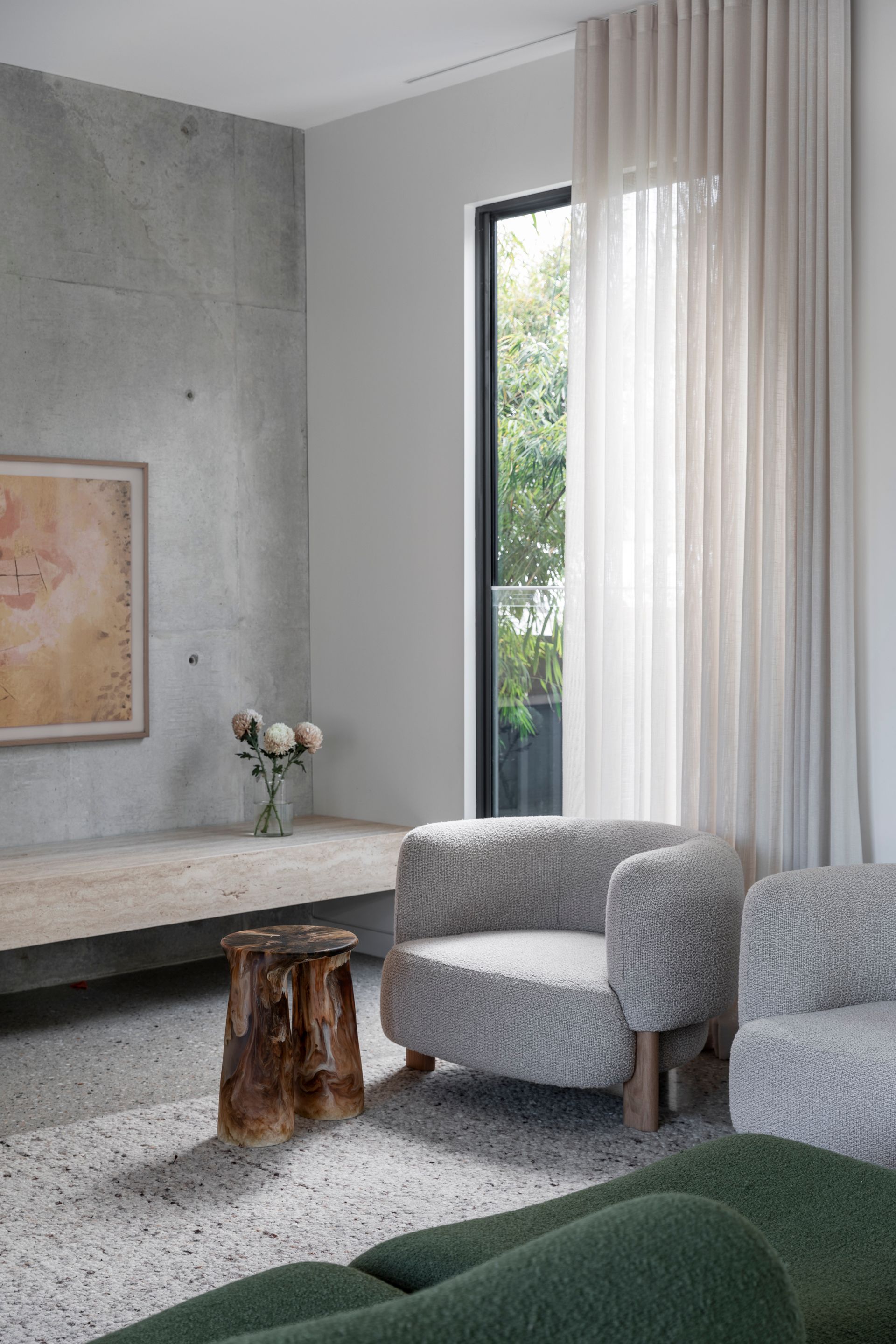 Modern living room with textured gray armchairs, tree stump side table, and sheer curtains by a window — Make The Mark Building Services in Illawarra, NSW