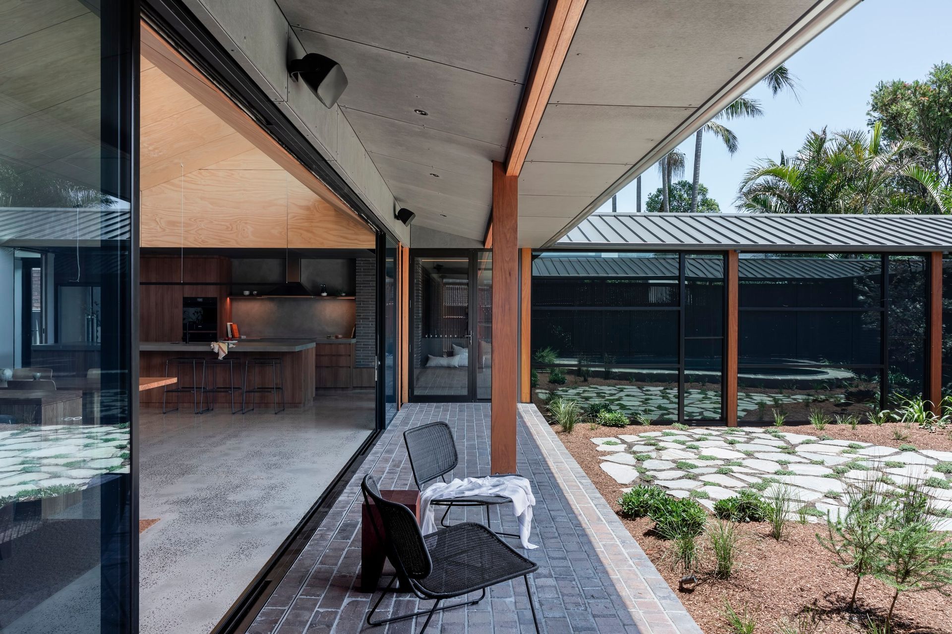 Outdoor patio with chairs, looking into a modern kitchen, with a garden view — Make The Mark Building Services in Illawarra, NSW