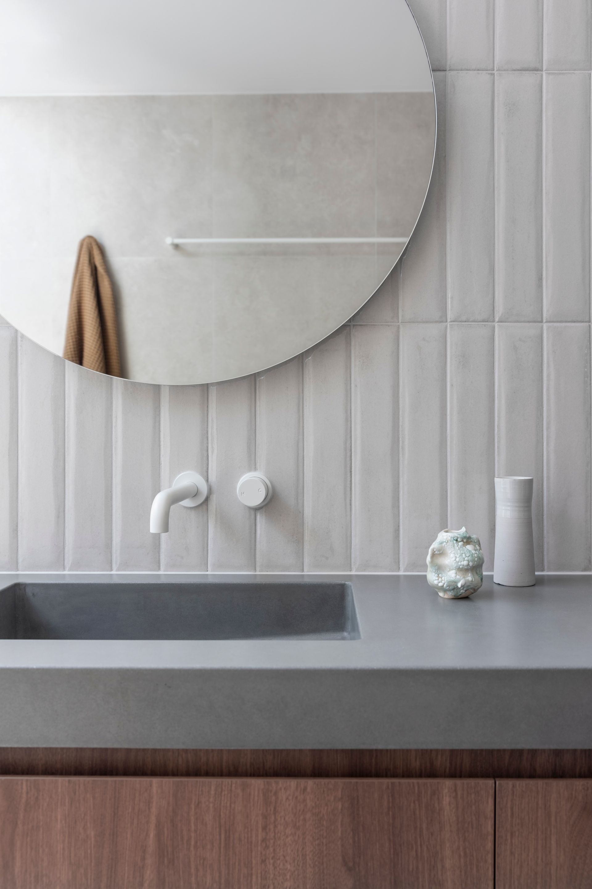 Modern bathroom with gray countertop, white fixtures, wood cabinet, and round mirror — Make The Mark Building Services in Illawarra, NSW
