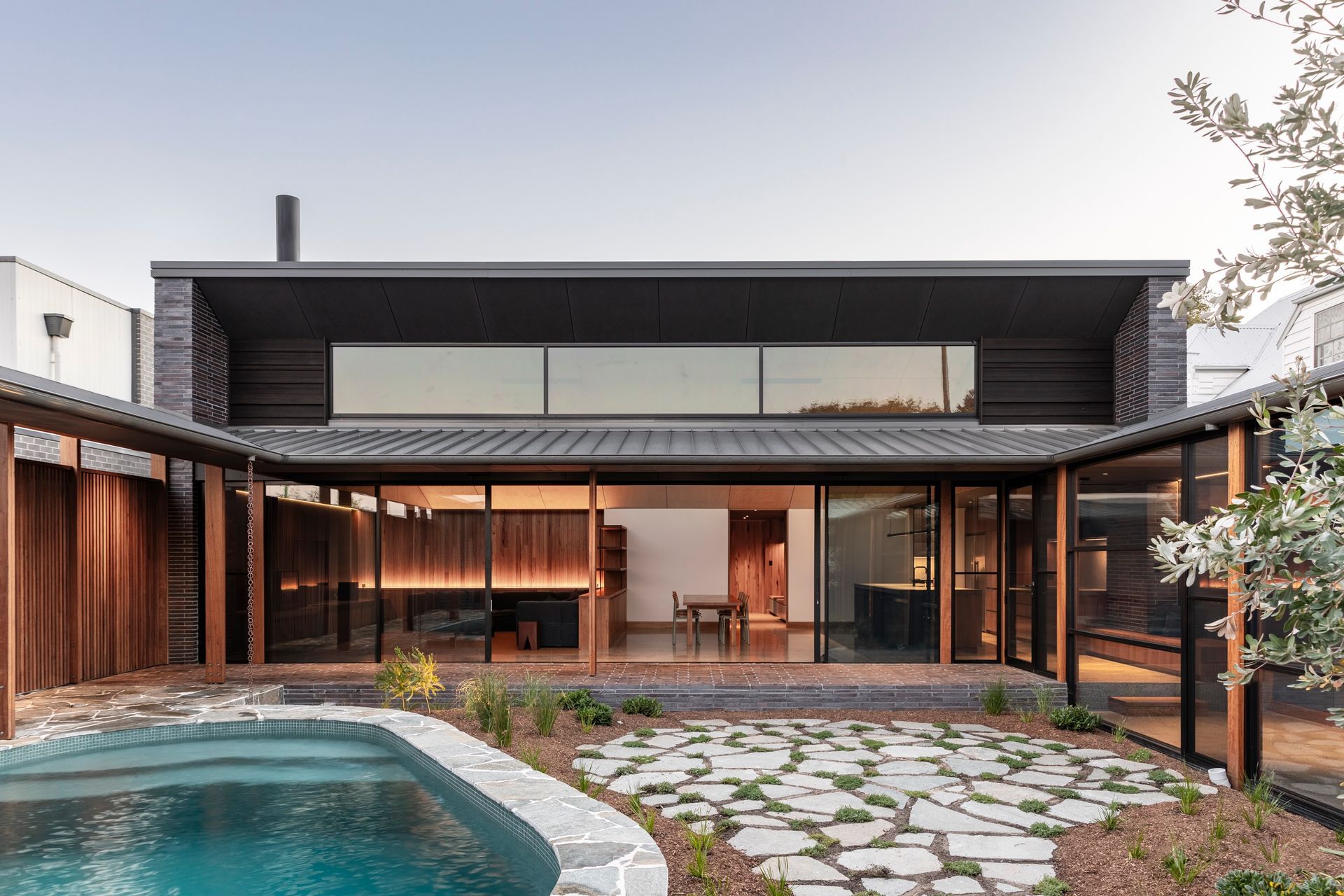 Exterior view of a modern home with a pool, glass doors, and wooden accents — Make The Mark Building Services in Illawarra, NSW