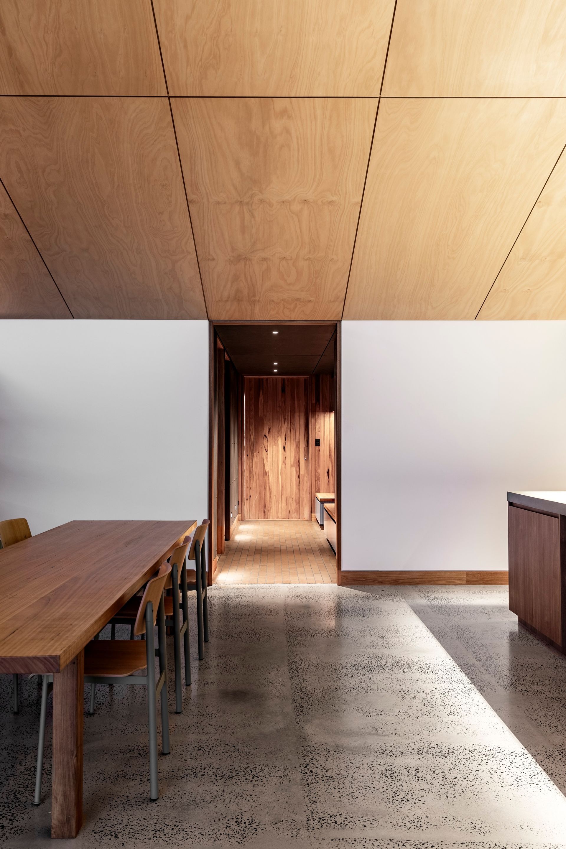 Interior view of a modern dining area with a wooden table, concrete floor, and wood panel ceiling — Make The Mark Building Services in Illawarra, NSW