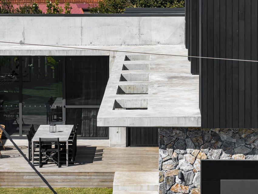Modern building exterior with concrete features, stone wall, and outdoor dining area — Make The Mark Building Services in Illawarra, NSW