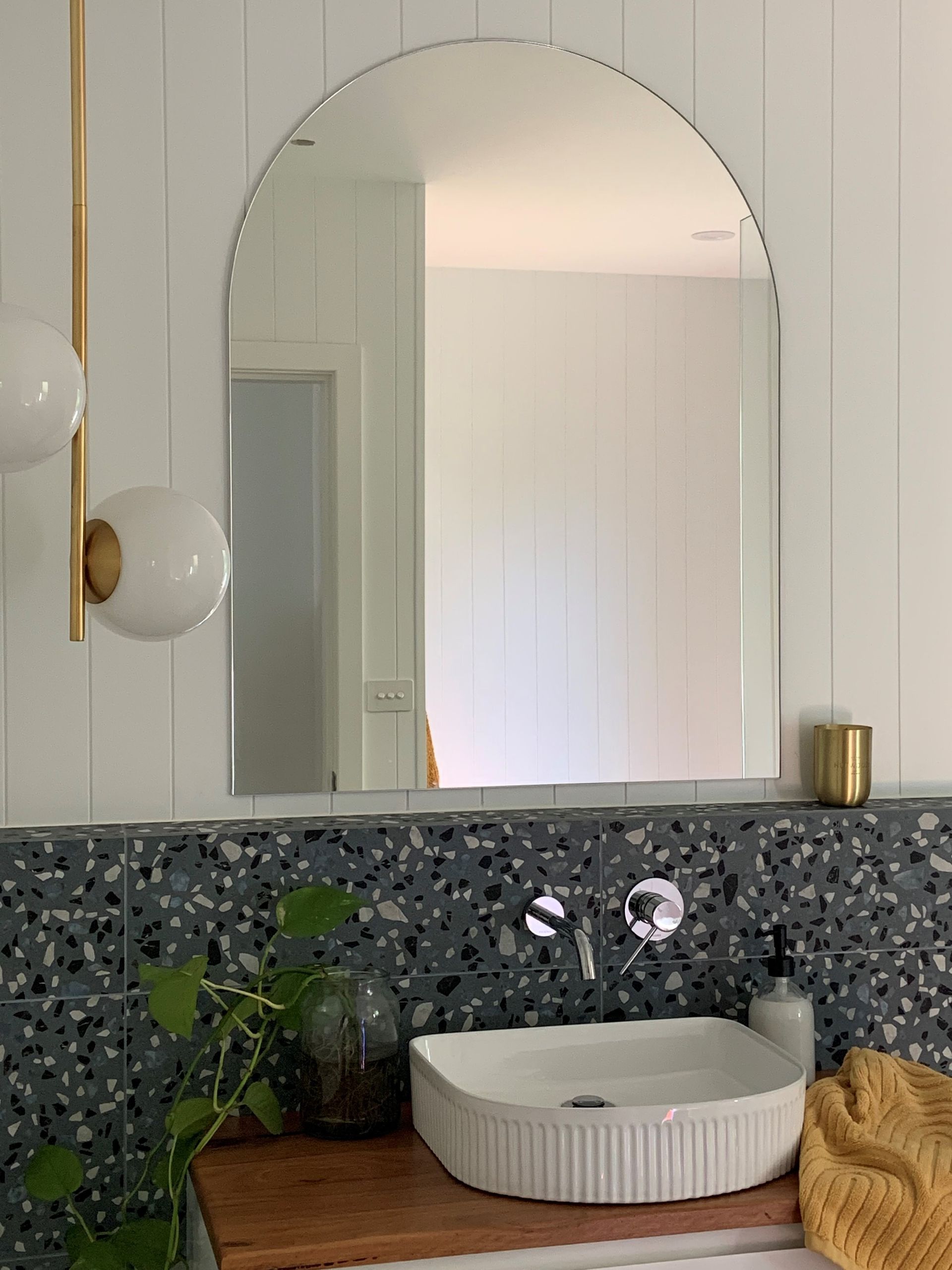 Bathroom with an arched mirror, white sink, and blue speckled tile backsplash - Make The Mark Building Services in Mangerton, NSW