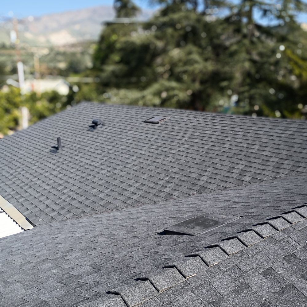 Person lifting a rolled black mat on a rooftop under bright daylight