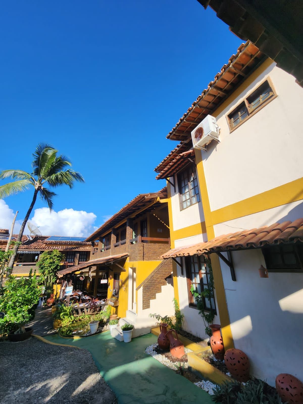 Um grande edifício com uma palmeira na frente-Pousada-A-Flor-Da-Terra