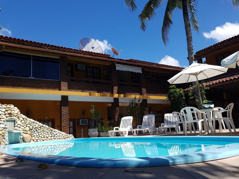 Uma piscina com cadeiras e guarda-sóis em frente a um prédio-Pousada-A-Flor-Da-Terra