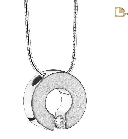 Silver circular pendant necklace with a cutout keyhole-like design and a small dangling charm