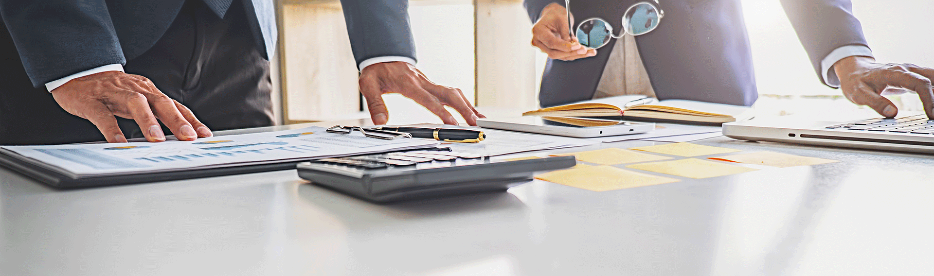A group of people are working on a financial success plan on a table.