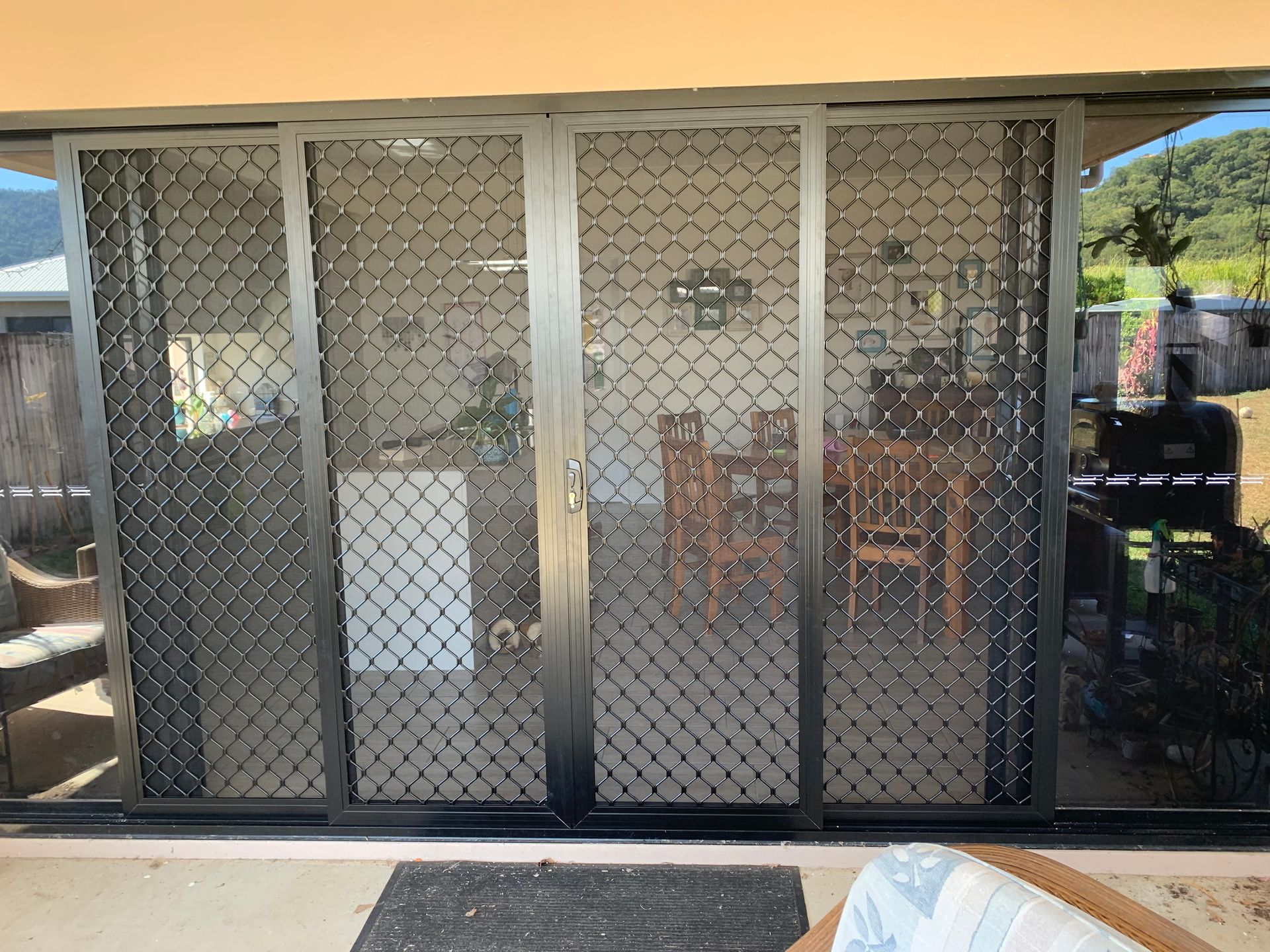 A sliding glass door with a mesh screen is open to a dining room.