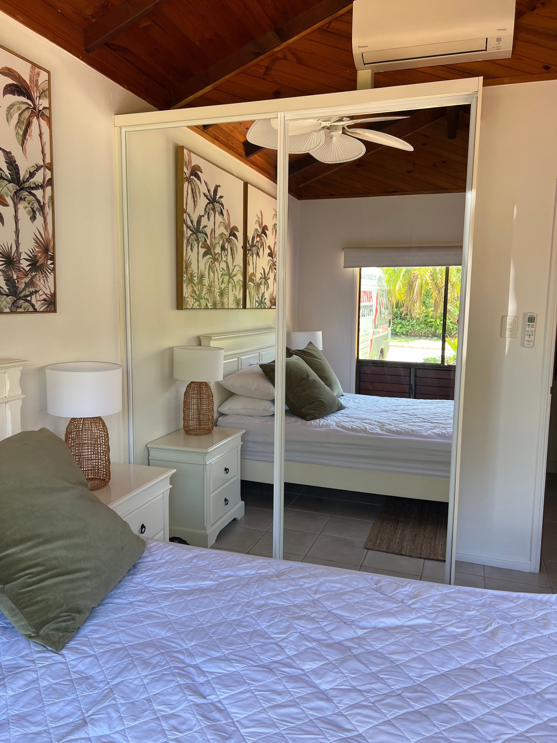 A bedroom with a bed , nightstand , mirror and ceiling fan.