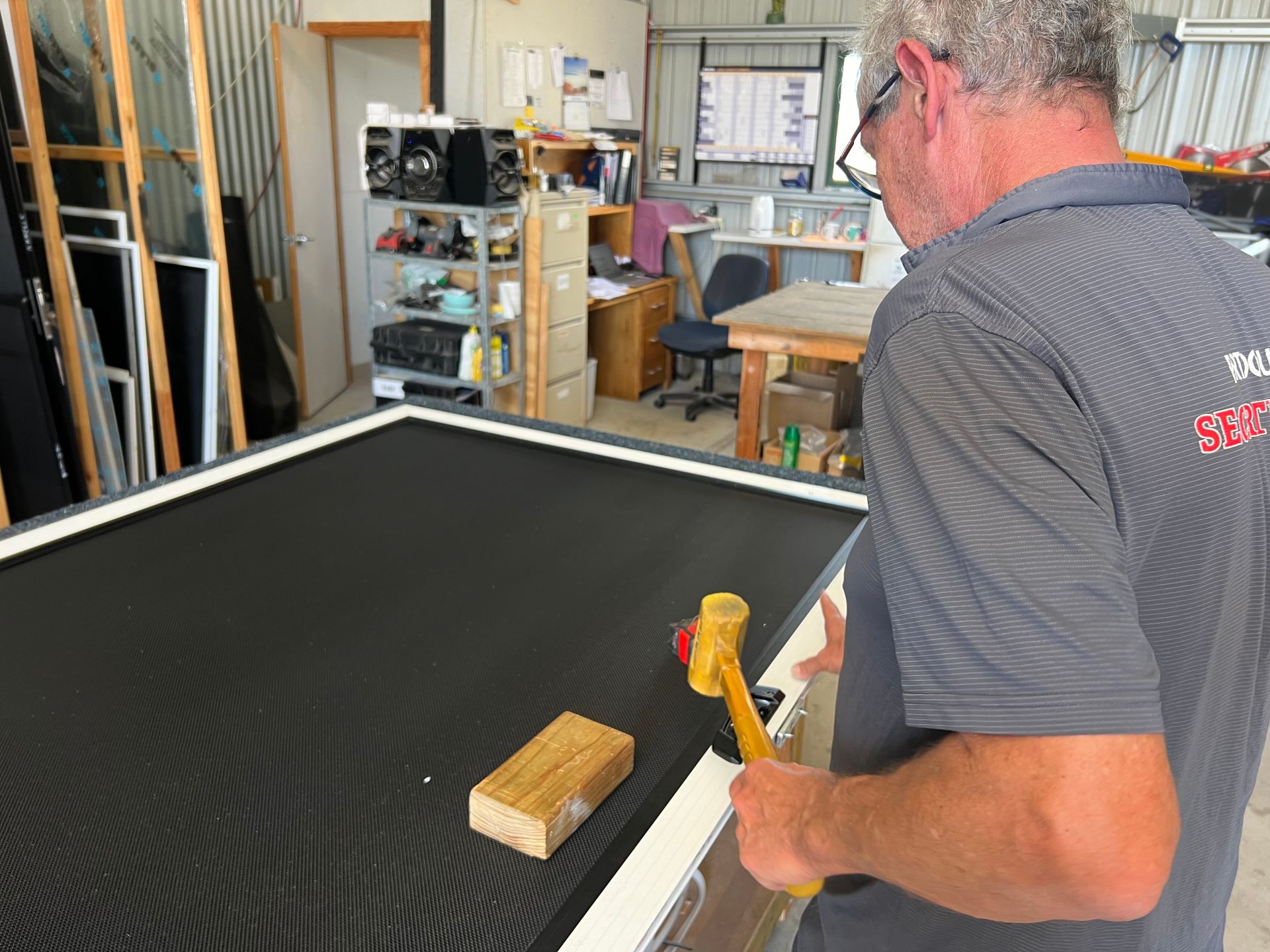 A man is working on a piece of wood with a hammer.