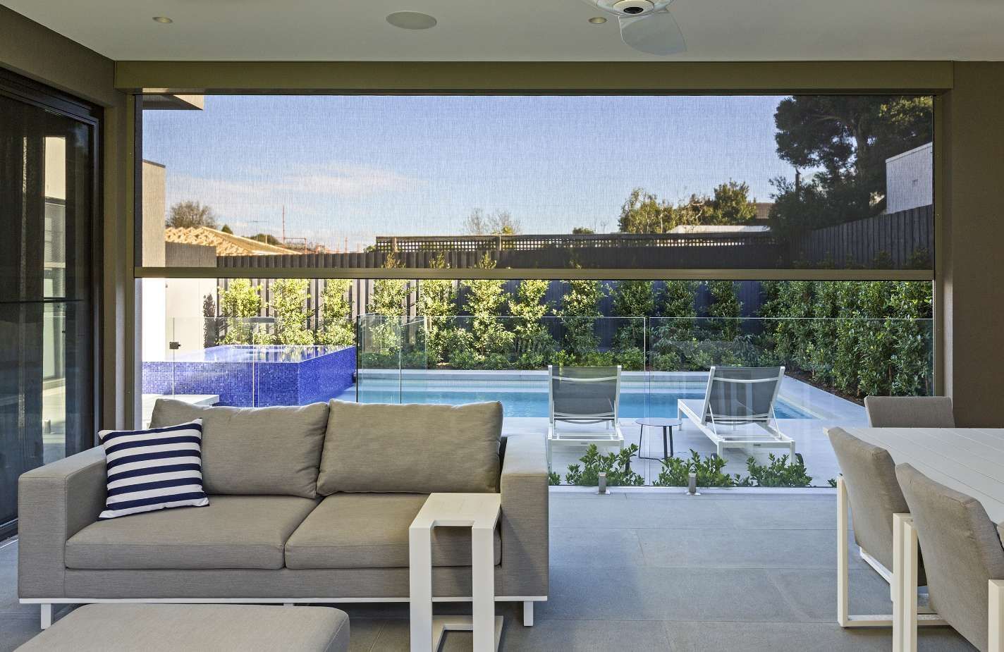 A living room with a couch and a table with a view of a pool