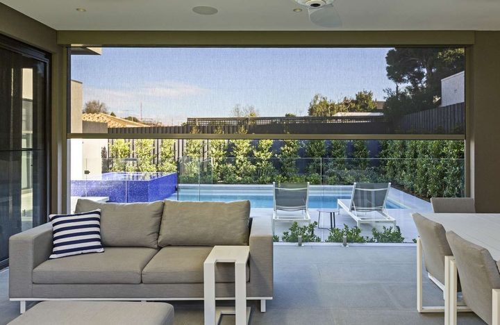A living room with a couch and a table with a view of a pool