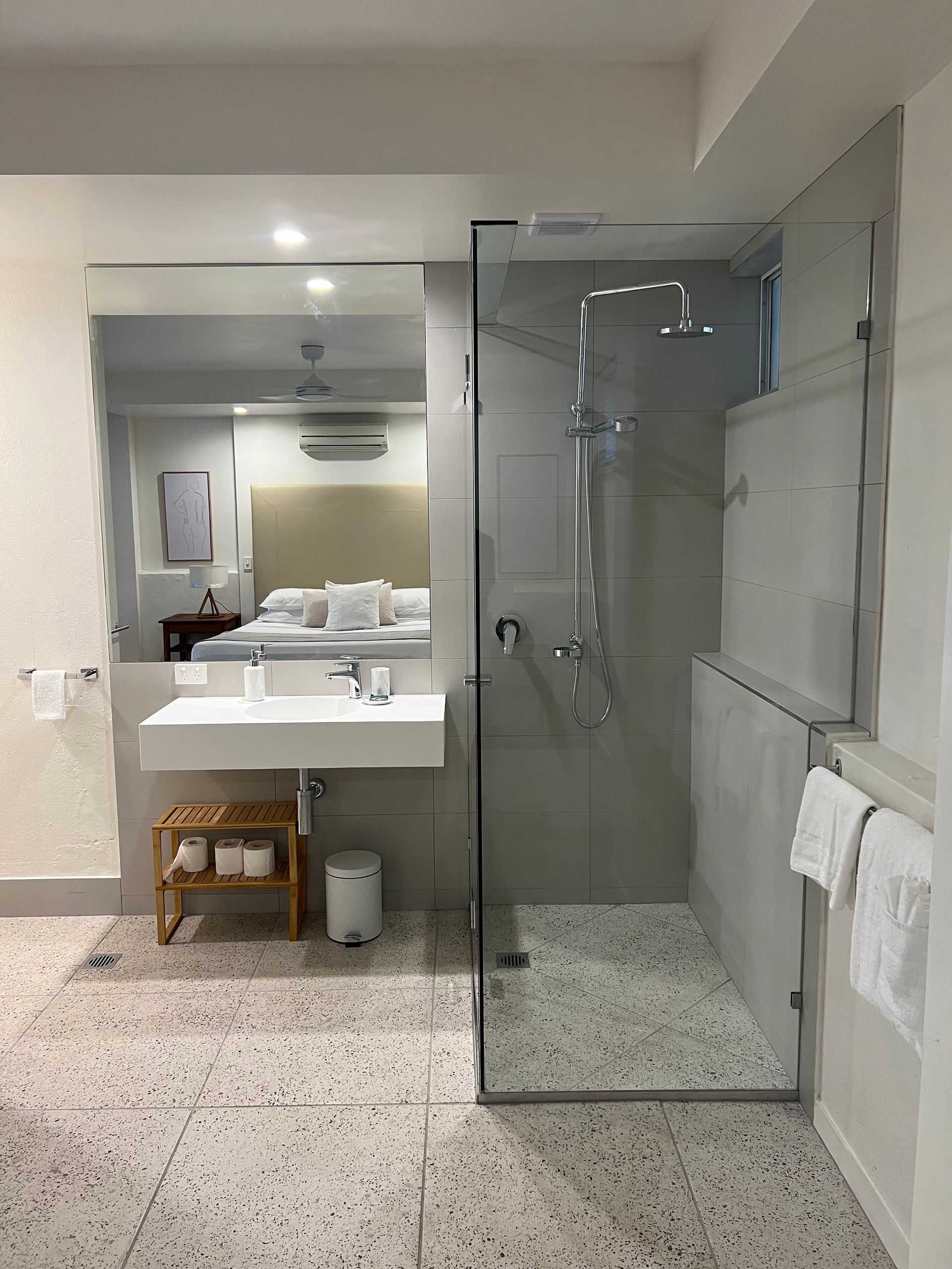 A bathroom with a walk in shower , sink and mirror.