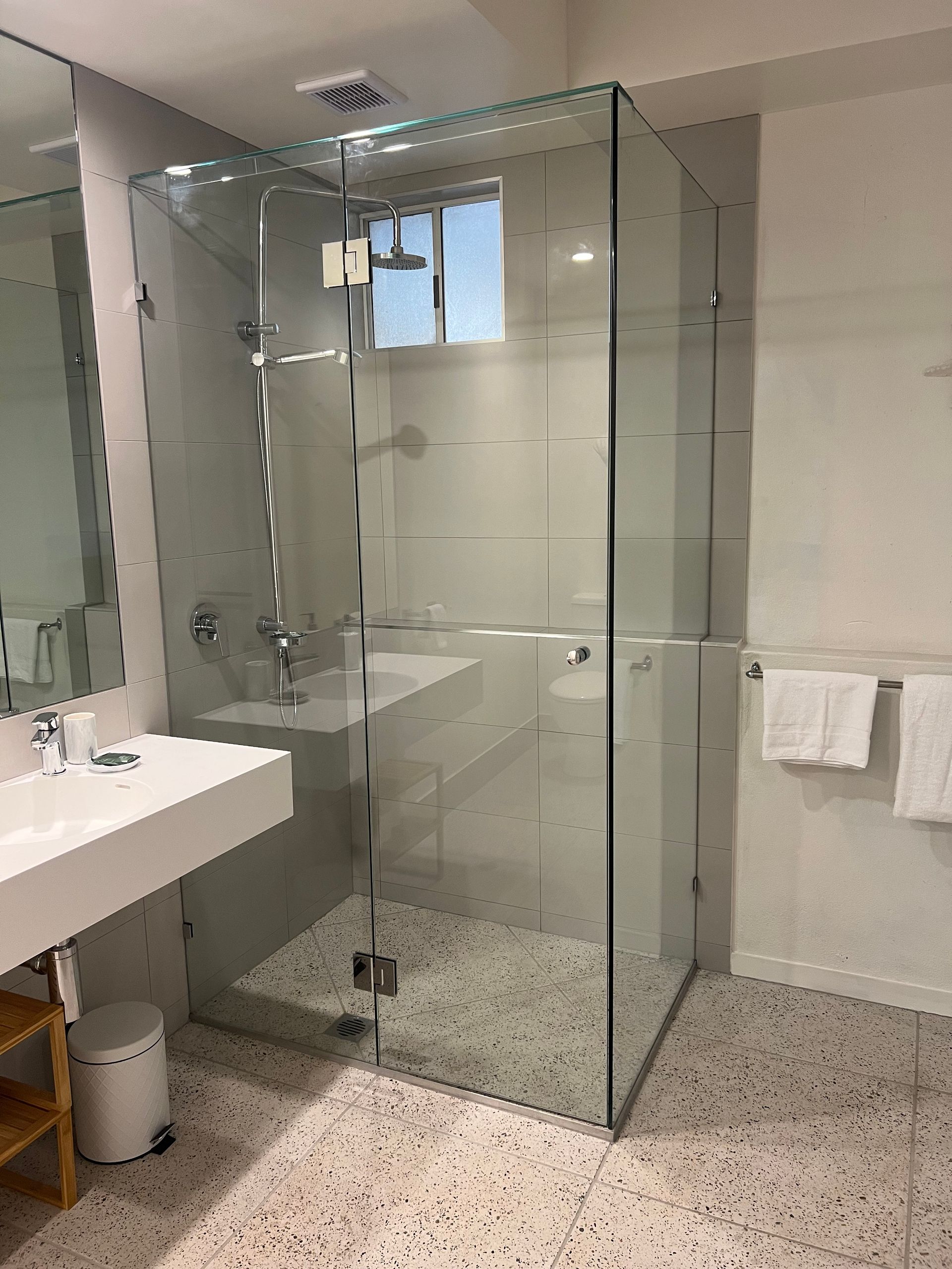 A bathroom with a walk in shower , sink and mirror.