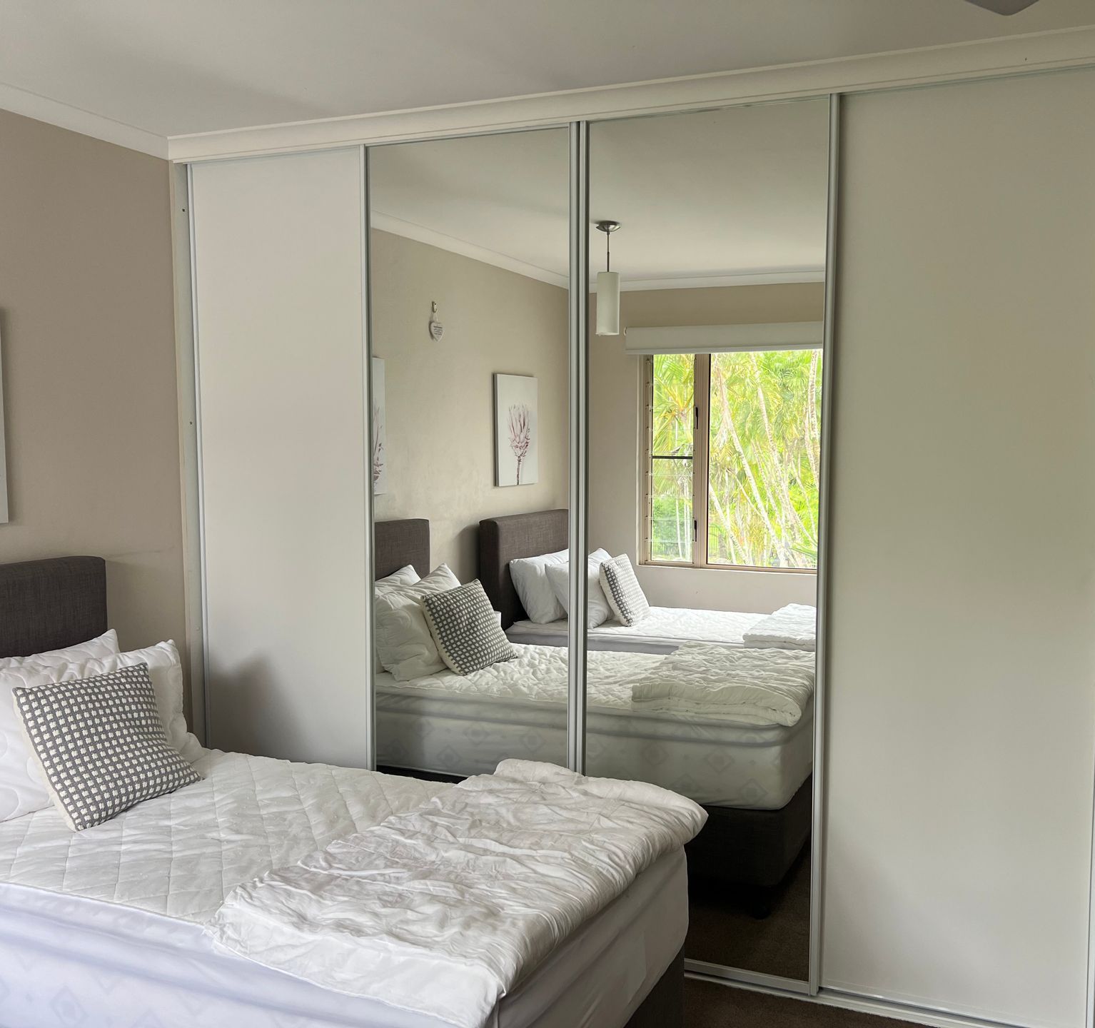 A bedroom with two beds and a mirrored wardrobe