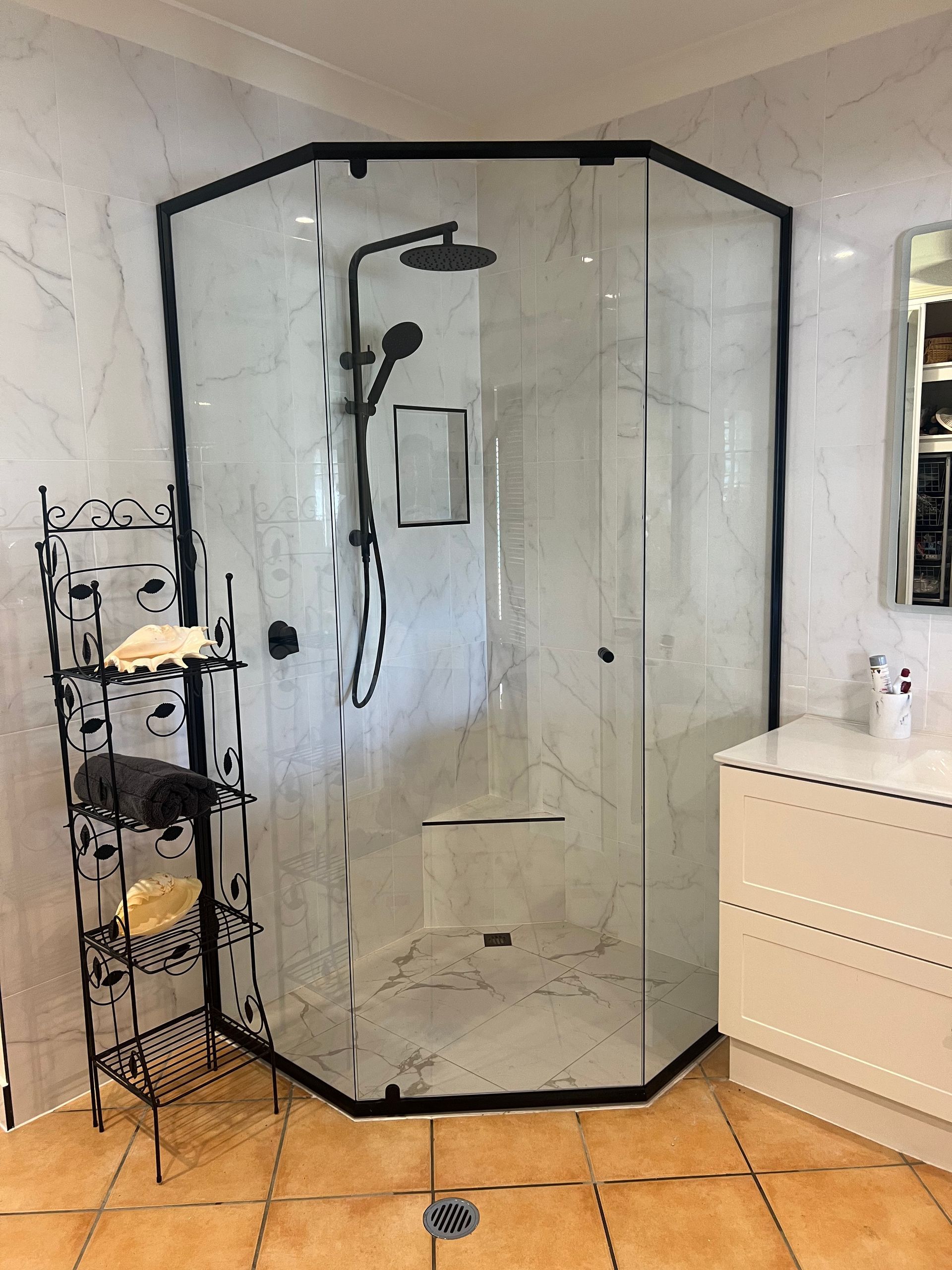 A bathroom with a shower , sink , mirror and towel rack.