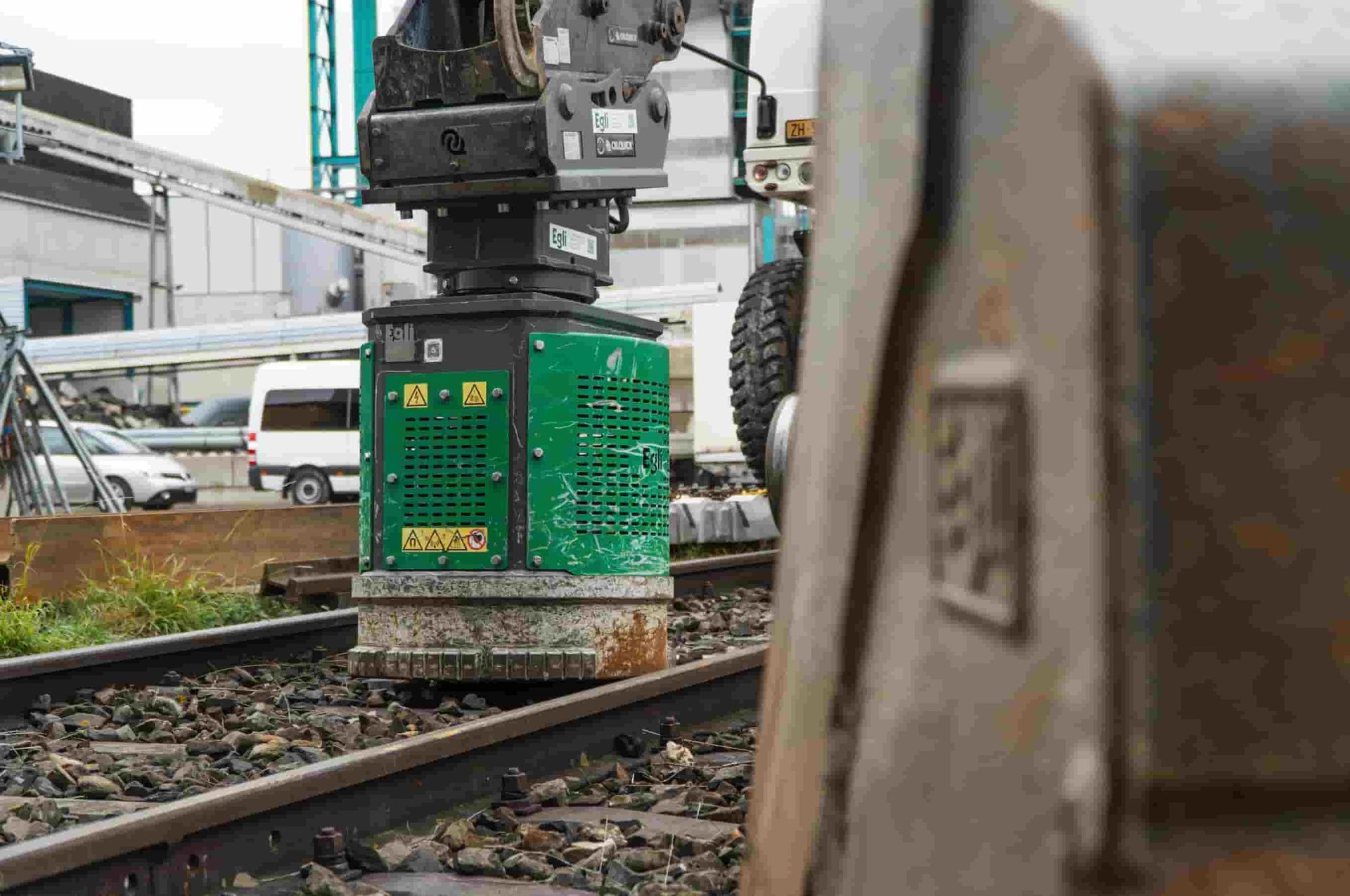 Close-up of Egli hydraulic magnet on railway track with excavator bucket in frame, supplied by Harrybilt Engineering