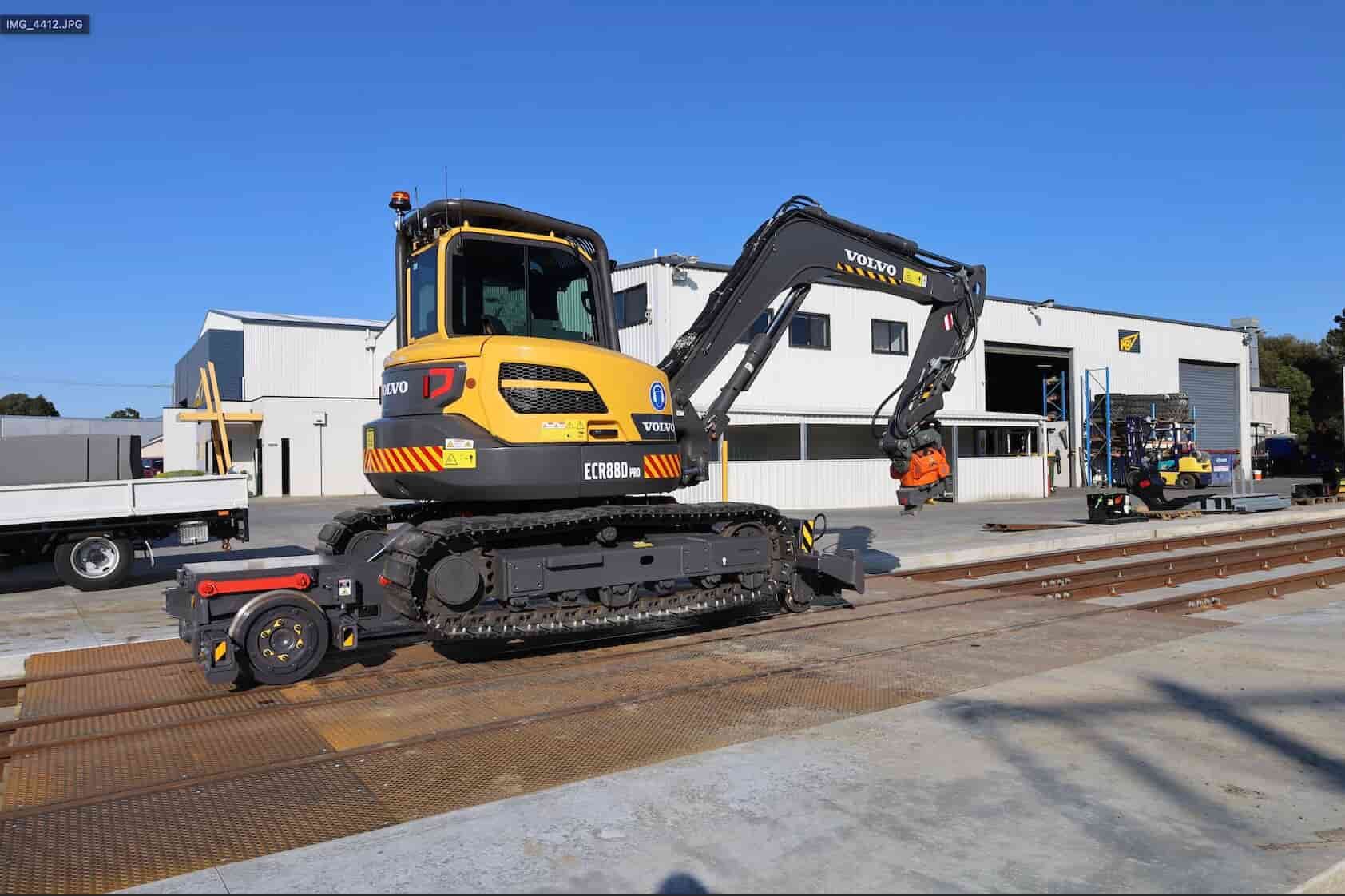 Compact excavator mounted on a rail guidance trailer undergoing testing on Harrybilt's rail test track.