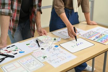 Two people at a table are planning a design, with sketches and notes spread out.