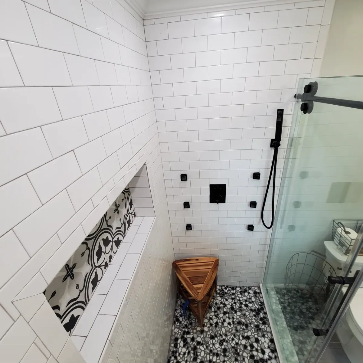 A bathroom with white tiles and a walk in shower
