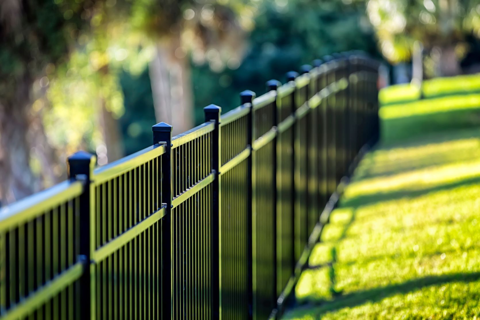 A black metal fence surrounds a lush green field.