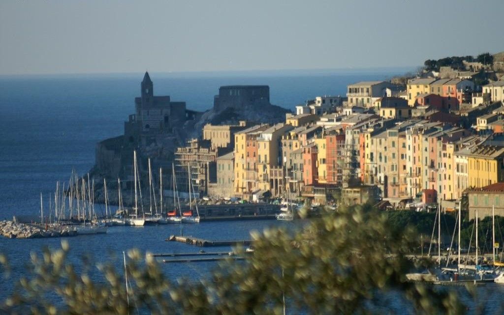 Città costiera italiana con edifici colorati, porto e barche.