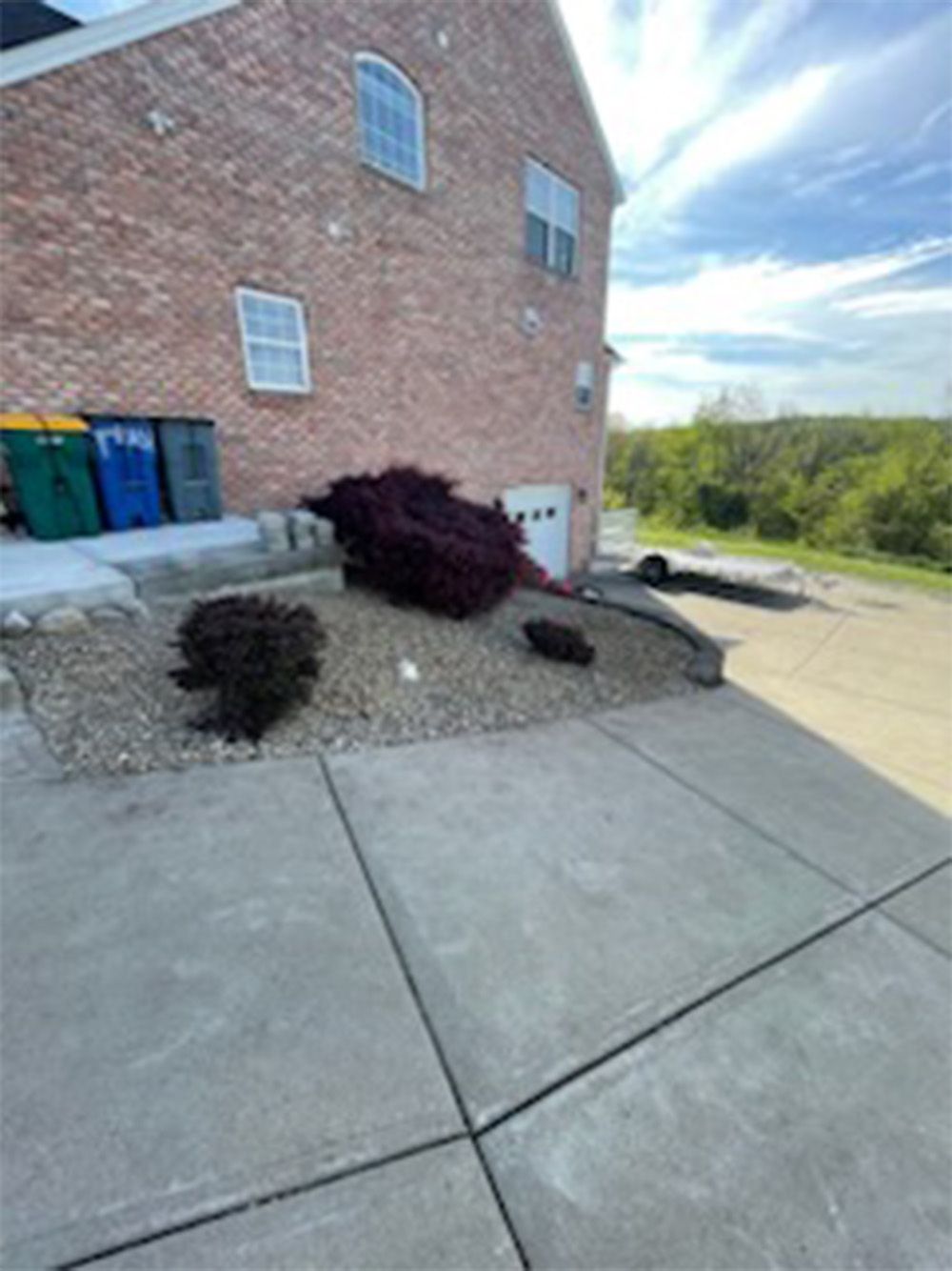 A brick house with a concrete driveway in front of it