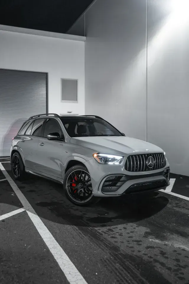 Silver Mercedes SUV parked outside a modern building at night