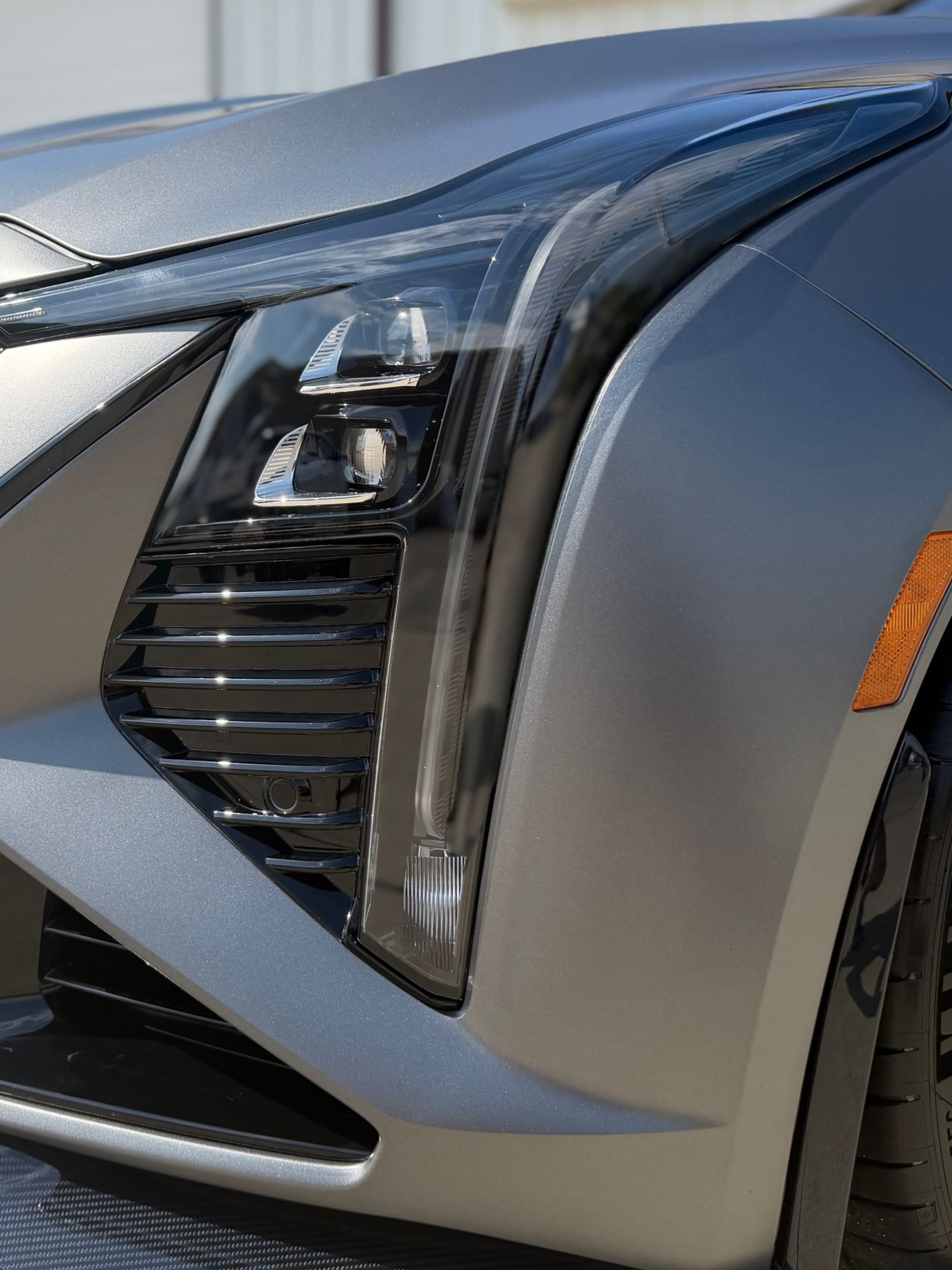 Close-up of a silver car’s front headlight and grille detail
