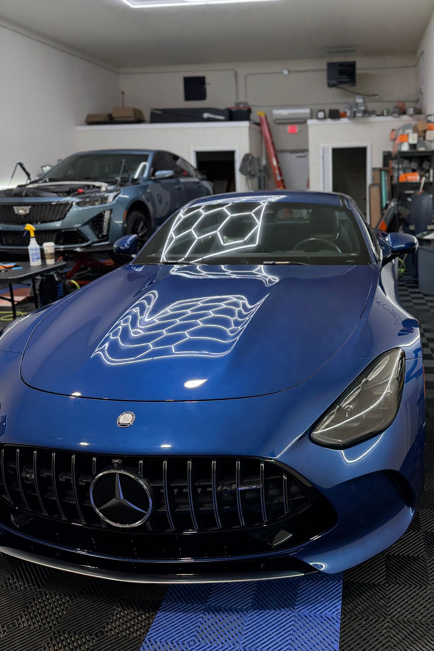 Blue Mercedes sports car in a garage with other vehicles in the background