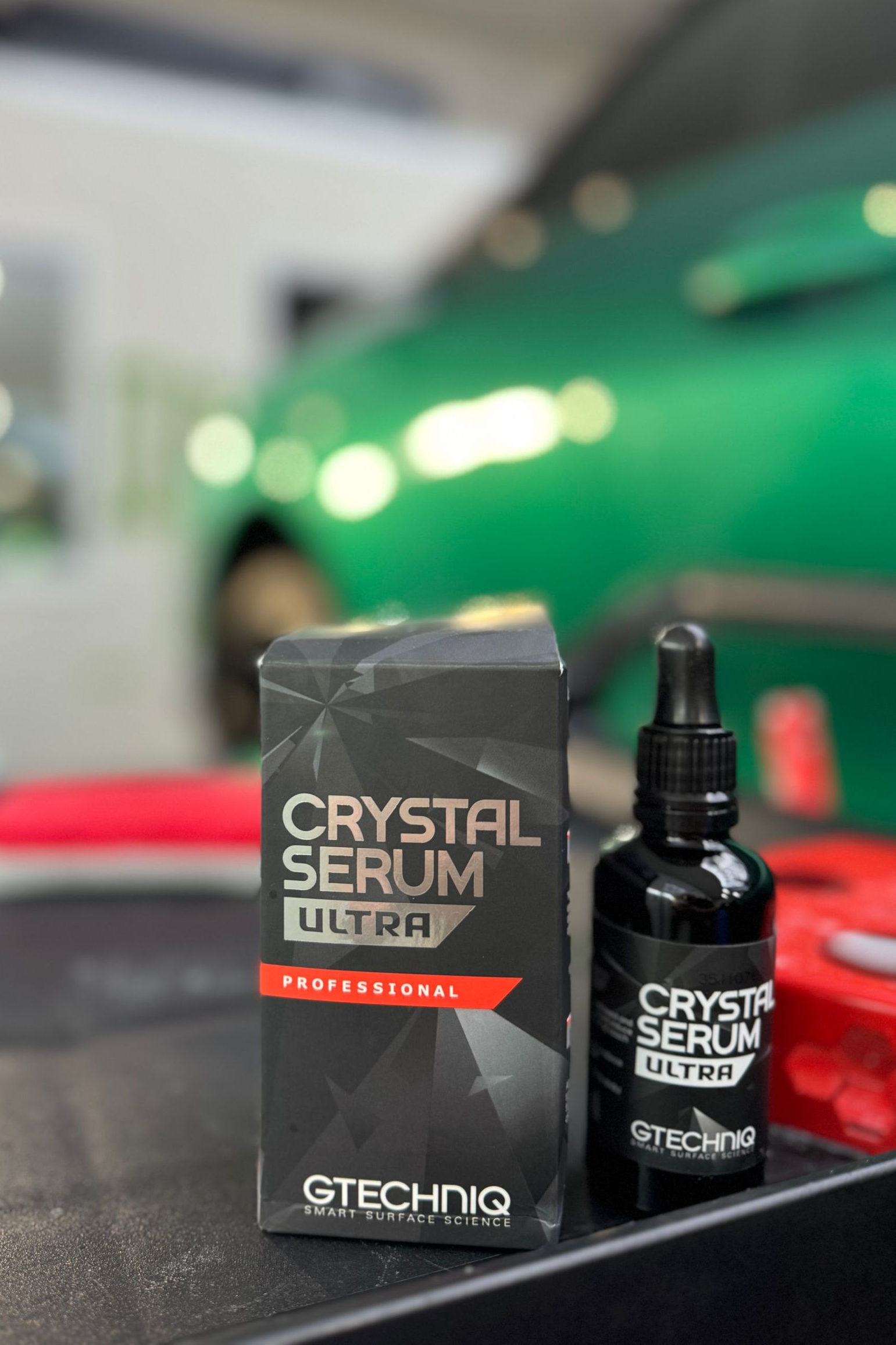 Crystal Serum Ultra ceramic coating kit with bottle and box beside a green car.