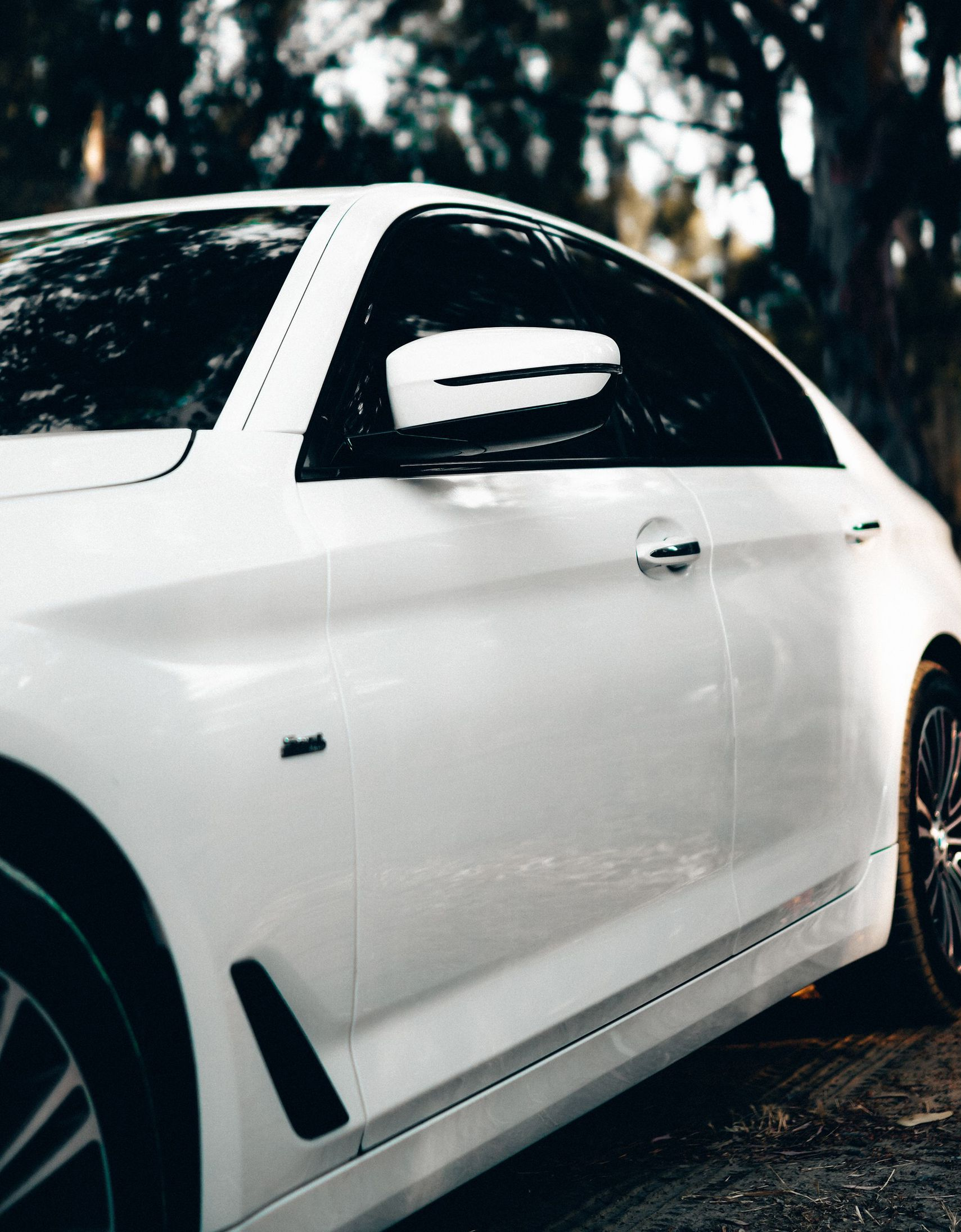 Gloved hand polishing a white sports car headlight with a gray cloth