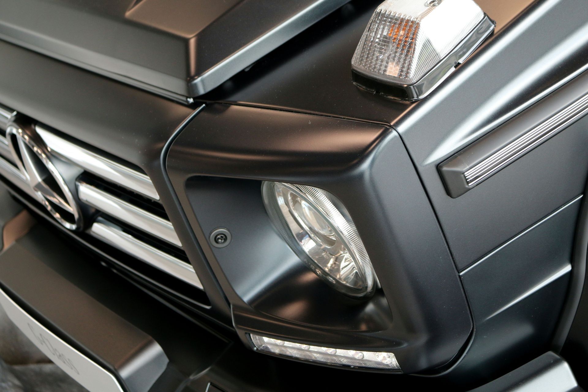Close-up of a black SUV front corner with headlight and grille detail
