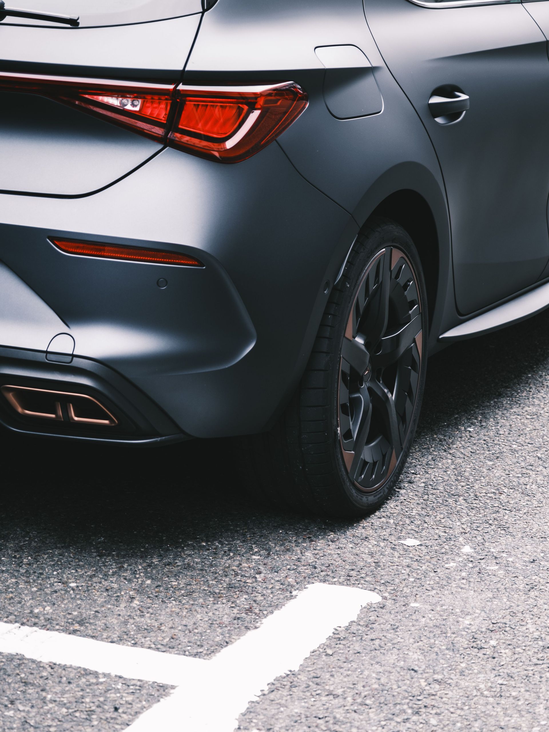 Rear view of a dark gray sedan parked on a painted street line