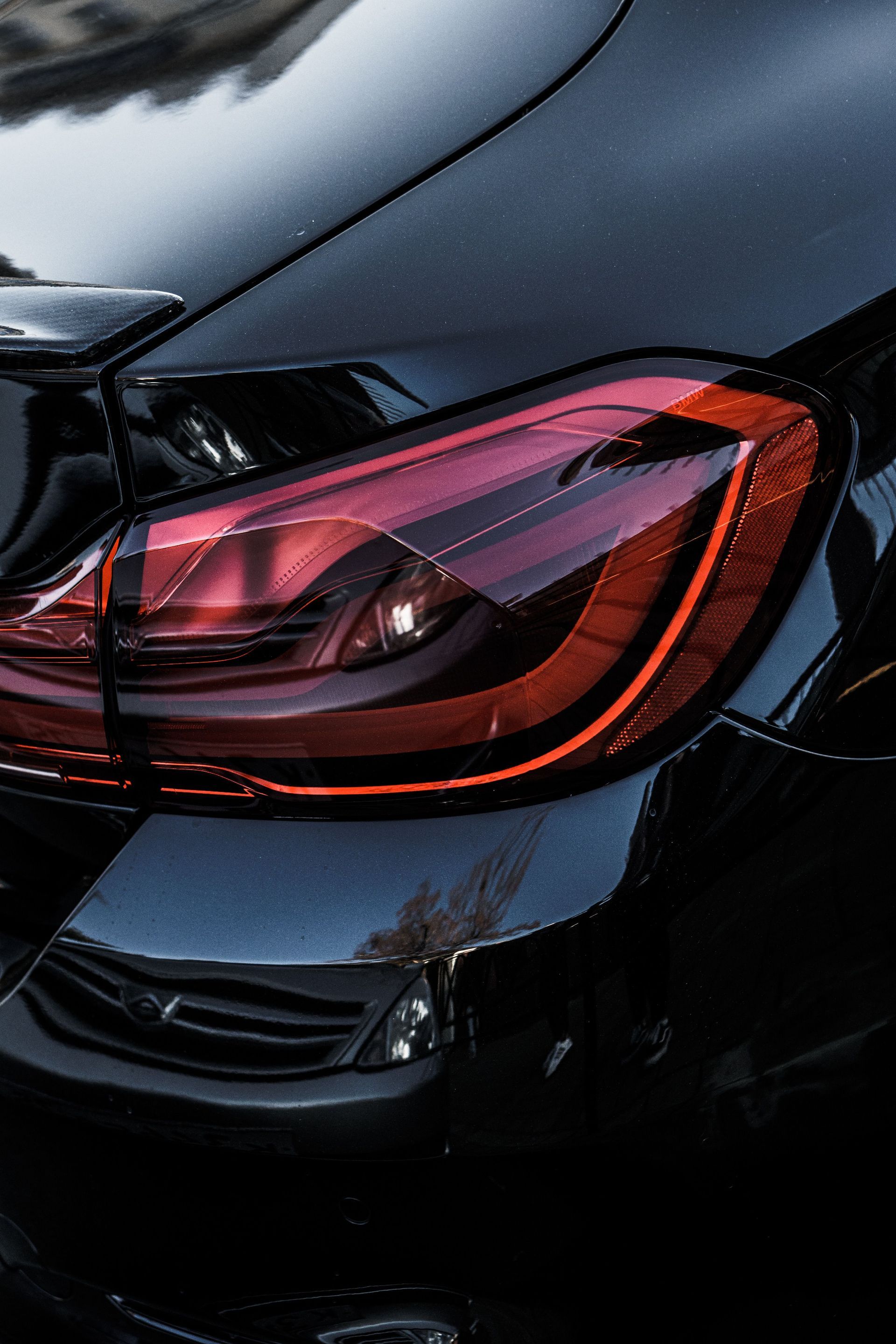 Close-up of a black car’s rear taillight with red illuminated accents