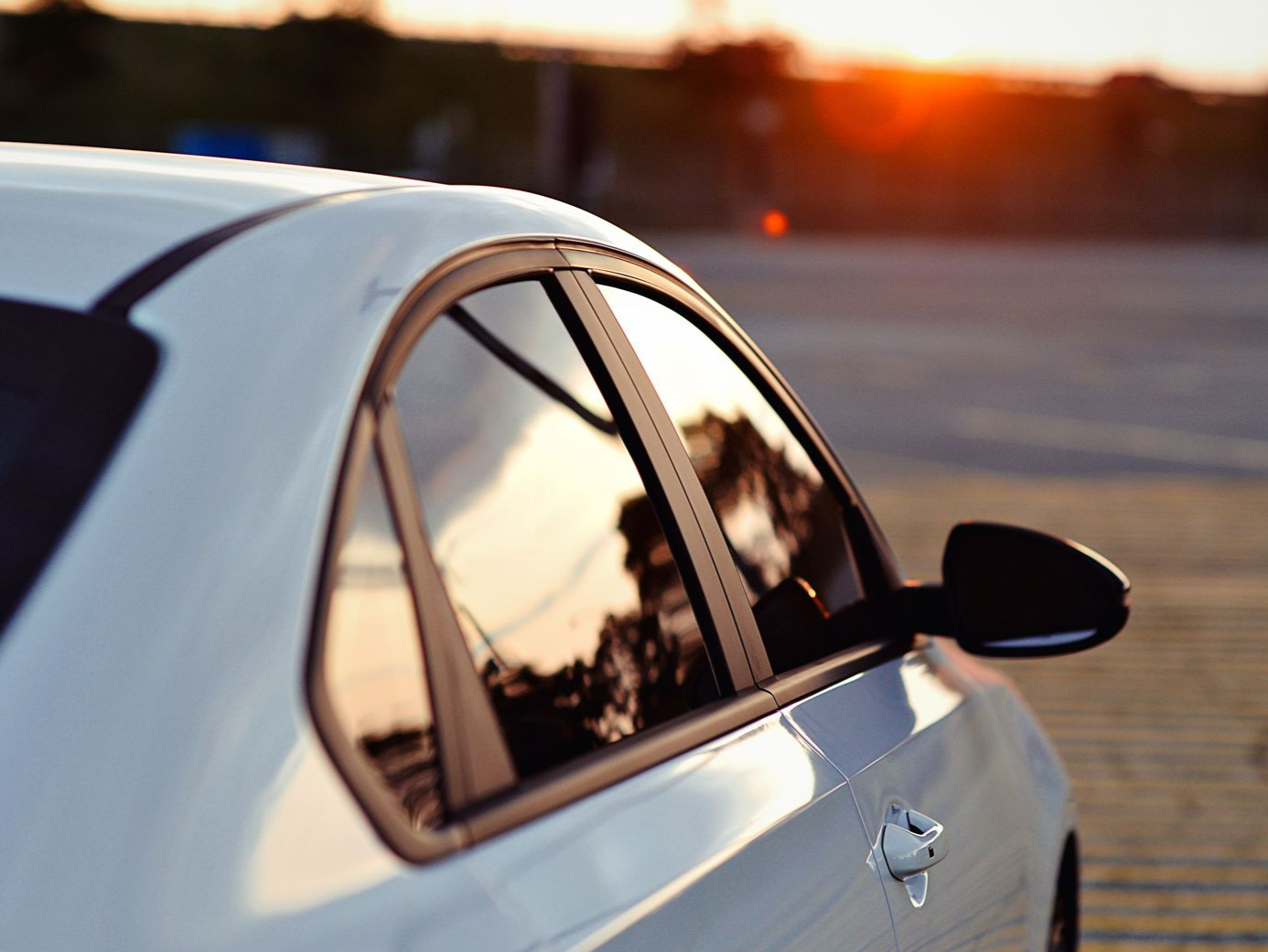 White car side view at sunset with warm reflections in the window and mirror
