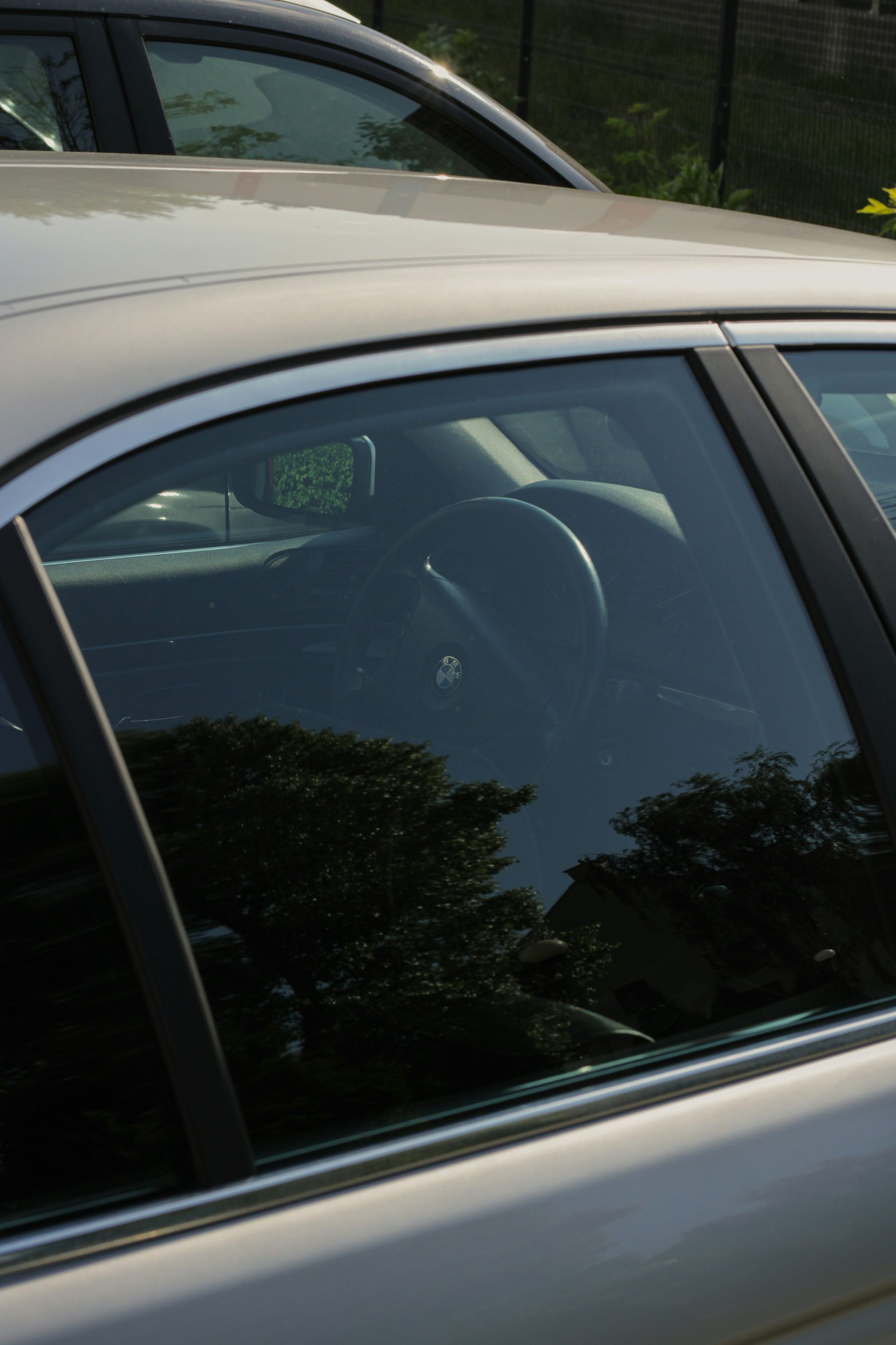 Installer working on vehicle window tint inside a white van, wearing a black cap and shirt