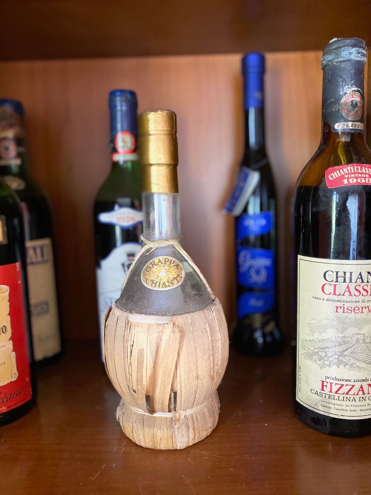 A classic bottle of wine is resting on a shelf alongside other bottles.