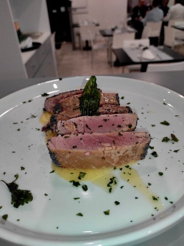 Fettine di carne scottate in padella con asparagi e salsa, servite in un piatto bianco da ristorante.