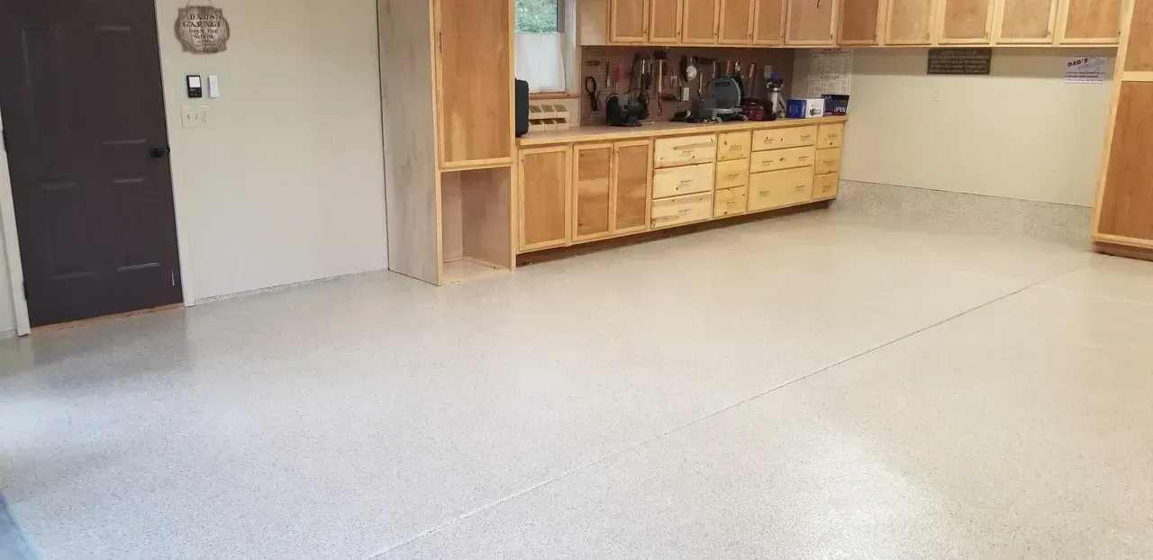 Empty kitchen with light wood cabinets and a speckled white floor