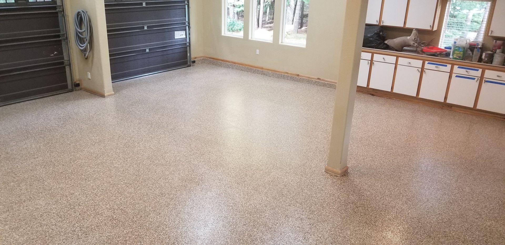 Empty room with speckled terrazzo floor, windows, and a support column.