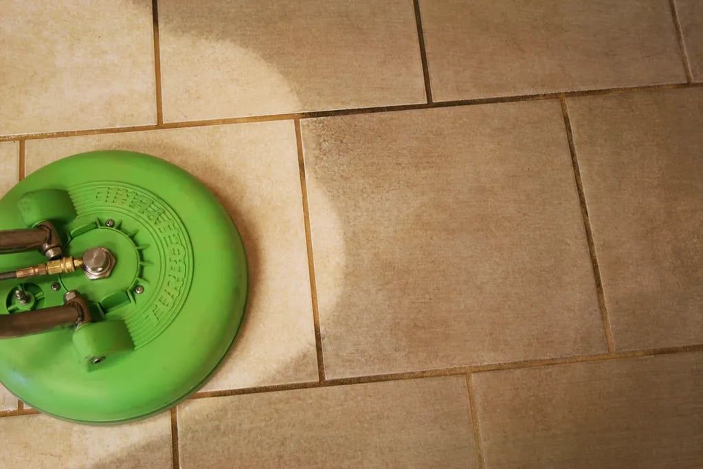 Green robotic vacuum on beige tiled floor indoors