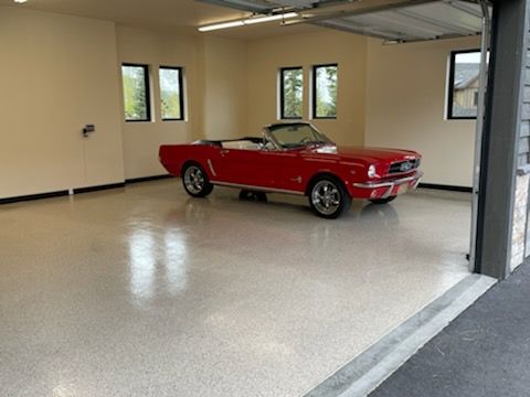 Red classic convertible parked in a clean, empty garage with beige walls and windows.